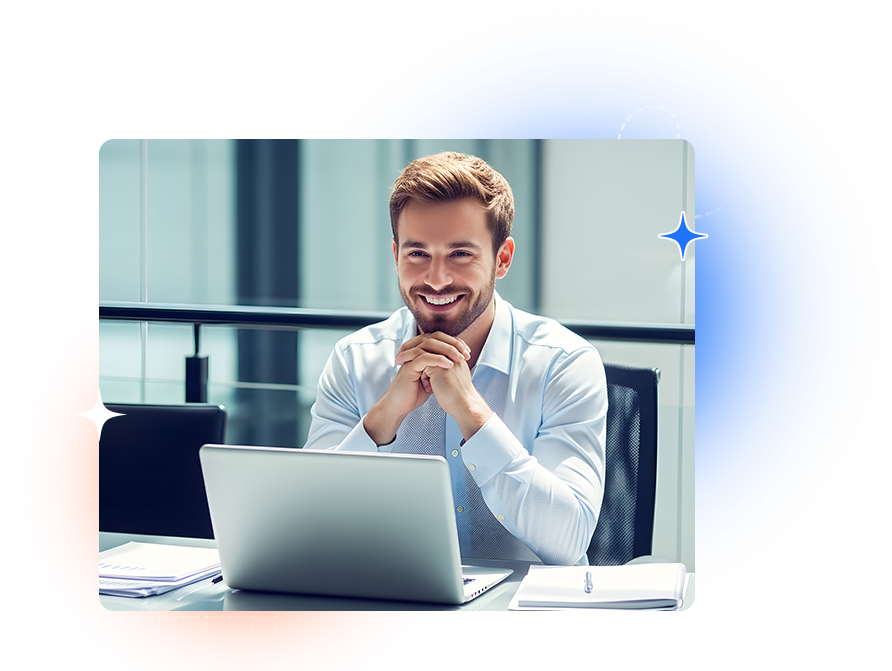 A smiling man at a desk behind an open laptop in a bright office